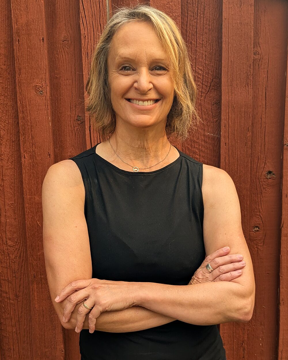 Anne Marie Norling, standing against a red barn wall